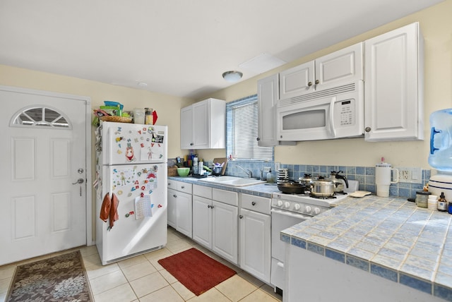 92-8821 Orchid Pkwy, Ocean View, HI 96737 - kitchen with white appliances, a sink, white cabinetry, light tile patterned floors, and tile countertops