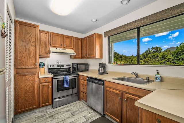 5301 Ka Haku Rd Unit 112, Princeville, HI 96722 - kitchen with appliances with stainless steel finishes, ventilation hood, a sink, light wood-style flooring, and brown cabinets