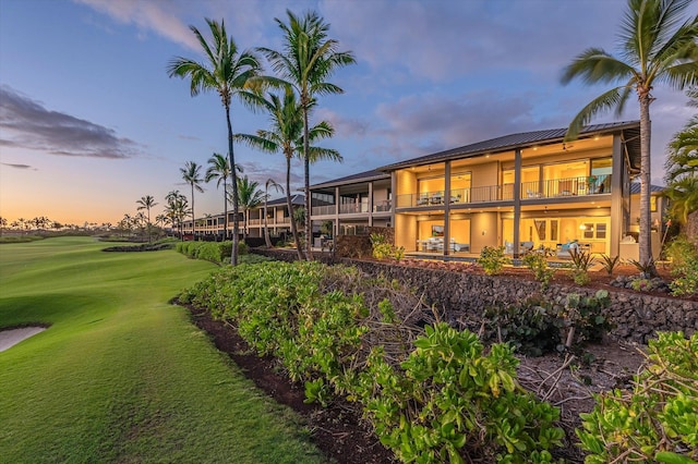 73-4804 Hinahina Rd Unit 13, Kailua-Kona, HI 96740 - back of property at dusk featuring stucco siding, a balcony, view of golf course, and metal roof