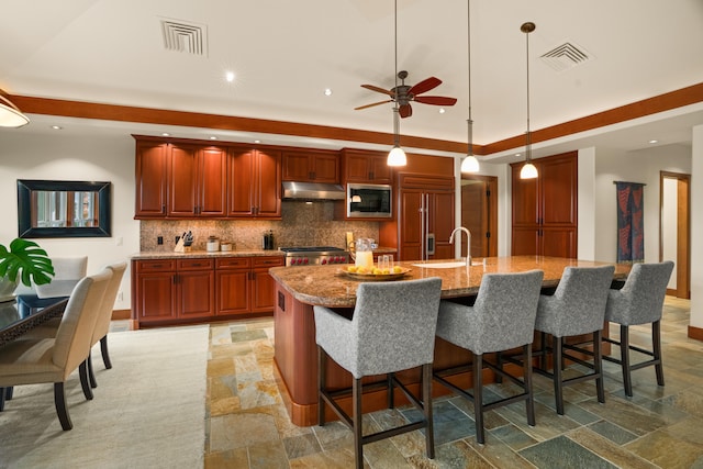 5385 Kolepa Pl, Koloa, HI 96756 - kitchen featuring built in appliances, under cabinet range hood, stone tile floors, backsplash, and a ceiling fan