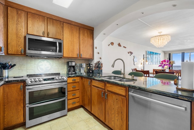 75-6106 Alii Dr Unit 208, Kailua-Kona, HI 96740 - kitchen with appliances with stainless steel finishes, a sink, brown cabinets, a chandelier, and tasteful backsplash