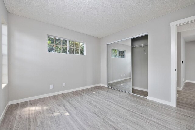 68-3890 Lua Kula St Unit 1104, Waikoloa, HI 96738 - unfurnished bedroom with wood finished floors, a closet, baseboards, and a textured ceiling
