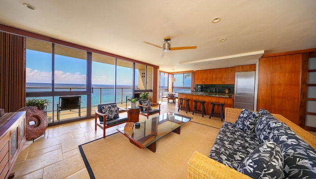 5050 Lawai Rd Unit 413, Koloa, HI 96756 - living room featuring a water view, a wall of windows, ceiling fan, stone tile flooring, and recessed lighting