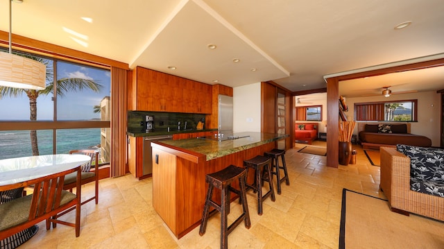 5050 Lawai Rd Unit 413, Koloa, HI 96756 - kitchen with a kitchen island, stainless steel appliances, a breakfast bar, brown cabinetry, and a sink