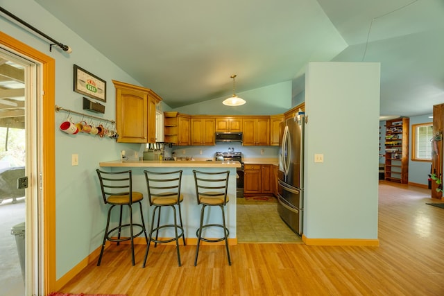 13-3477 Alapai St, Pahoa, HI 96778 - kitchen with appliances with stainless steel finishes, a peninsula, lofted ceiling, a breakfast bar area, and brown cabinetry