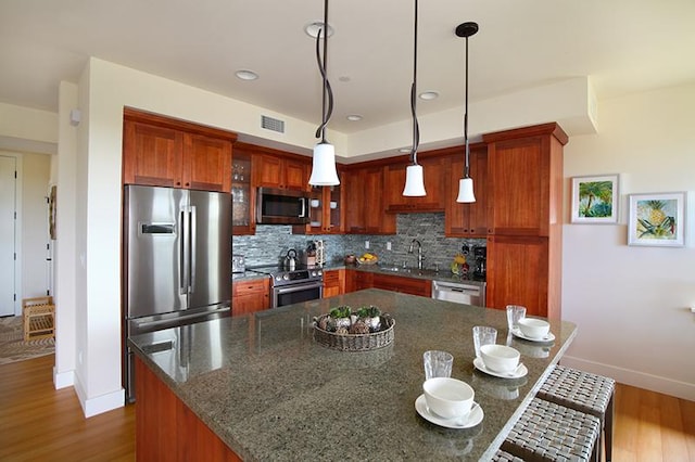 2611 Kiahuna Plantation Dr Unit 13B, Koloa, HI 96756 - kitchen with appliances with stainless steel finishes, baseboards, wood finished floors, decorative backsplash, and pendant lighting