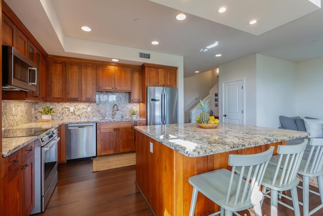 2611 Kiahuna Plantation Dr Unit 4G, Koloa, HI 96756 - kitchen featuring appliances with stainless steel finishes, a sink, dark wood finished floors, brown cabinetry, and decorative backsplash