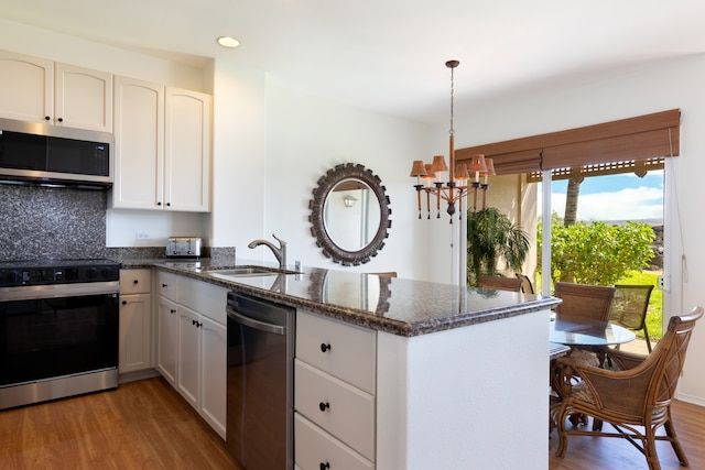 69-555 Waikoloa Beach Dr Unit 1704, Waikoloa, HI 96738 - kitchen with stainless steel appliances, a sink, a peninsula, a chandelier, and light wood-type flooring