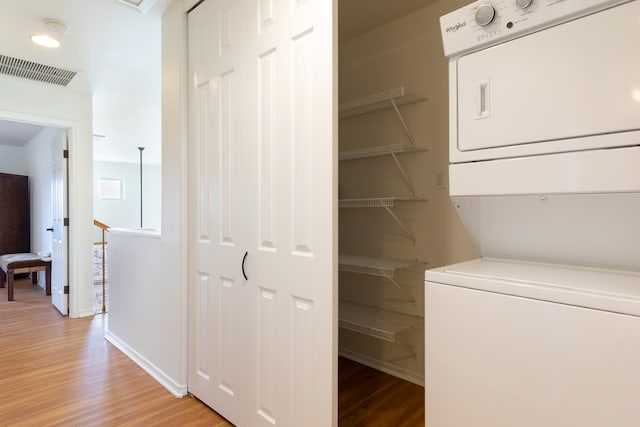 69-555 Waikoloa Beach Dr Unit 1704, Waikoloa, HI 96738 - laundry room with stacked washer and clothes dryer, light wood-style floors, and baseboards