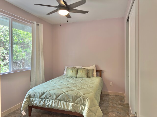94-5763 Awa Pae Pl, Naalehu, HI 96772 - bedroom with multiple windows, baseboards, stone finish floors, and ceiling fan
