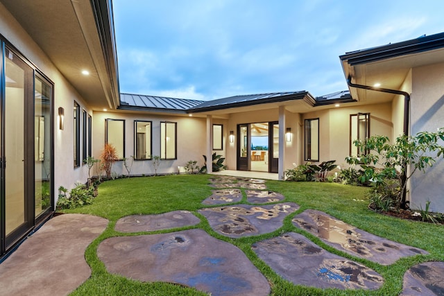 78-7029 Ola Mau St, Kailua-Kona, HI 96740 - rear view of property featuring a standing seam roof, stucco siding, a yard, and metal roof