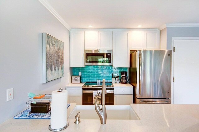 525 Aleka Lp Unit J2, Kapaa, HI 96746 - kitchen featuring stainless steel appliances, ornamental molding, backsplash, light countertops, and white cabinetry