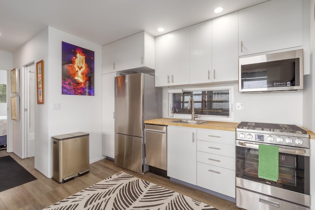 32-491 Piha Kahuku Rd, Ninole, HI 96773 - kitchen featuring appliances with stainless steel finishes, wood finished floors, a sink, white cabinetry, and recessed lighting