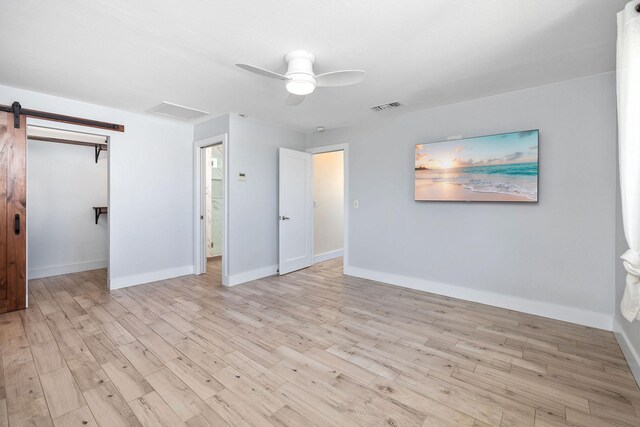 76-206 Kealoha St Unit 2A, Kailua-Kona, HI 96740 - unfurnished bedroom featuring wood finished floors, a barn door, ceiling fan, and baseboards