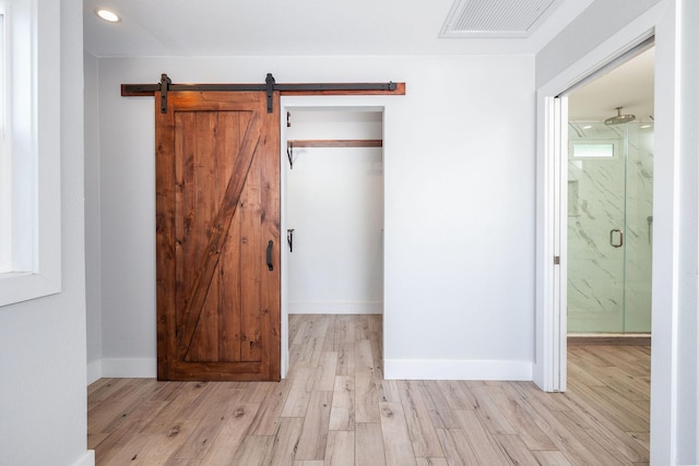 76-206 Kealoha St Unit 2A, Kailua-Kona, HI 96740 - unfurnished bedroom with a barn door, light wood-style flooring, a closet, recessed lighting, and baseboards