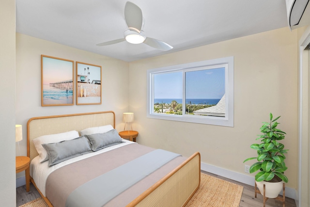 76-206 Kealoha St Unit 2A, Kailua-Kona, HI 96740 - bedroom featuring wood finished floors, baseboards, ceiling fan, and a wall mounted AC