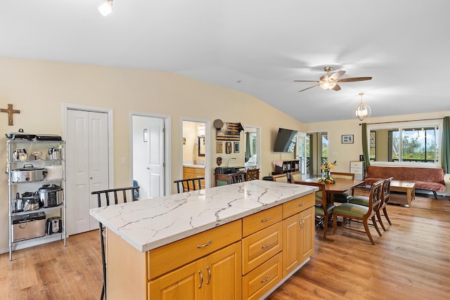 16-1580 39th Ave, Kurtistown, HI 96760 - kitchen featuring vaulted ceiling, light wood-type flooring, a ceiling fan, light stone counters, and a center island