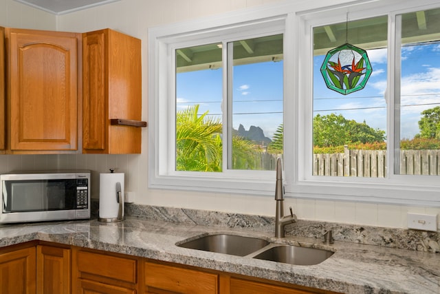 5587 Kawaihau Rd, Kapaa, HI 96746 - kitchen featuring stainless steel microwave, a sink, brown cabinetry, and tasteful backsplash