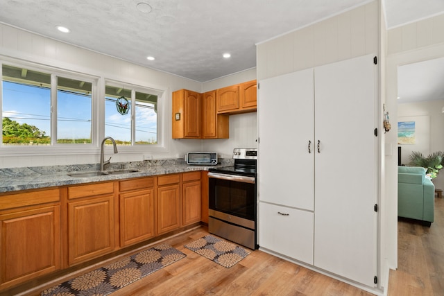 5587 Kawaihau Rd, Kapaa, HI 96746 - kitchen featuring stainless steel range with electric stovetop, a sink, light stone counters, light wood-type flooring, and brown cabinets