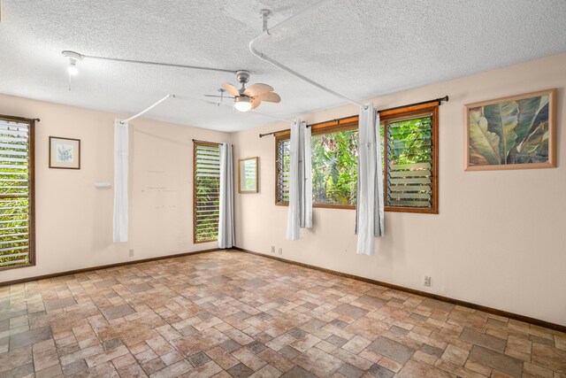 187 Lihau St, Kapaa, HI 96746 - unfurnished room featuring a ceiling fan, stone tile flooring, baseboards, and a textured ceiling