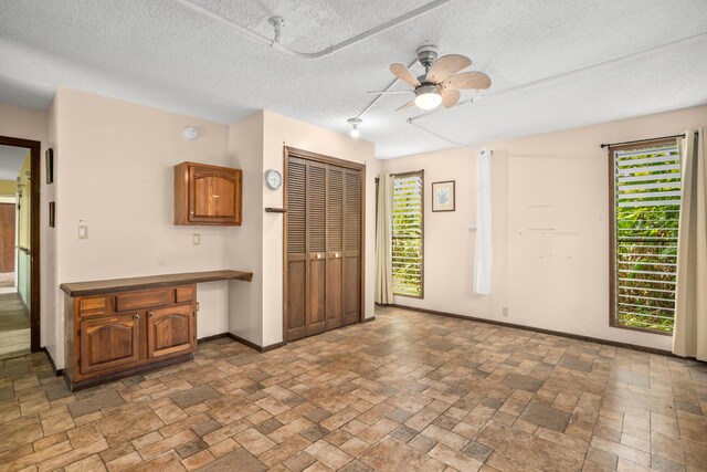 187 Lihau St, Kapaa, HI 96746 - foyer entrance with built in study area, stone tile floors, baseboards, ceiling fan, and a textured ceiling