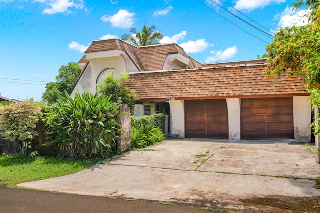 187 Lihau St, Kapaa, HI 96746 - front facade featuring mansard roof, concrete driveway, stucco siding, a shingled roof, and a garage