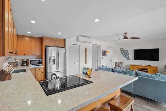 75-5719 Alii Dr Unit 307, Kailua-Kona, HI 96740 - kitchen with stainless steel appliances, a sink, a wall mounted AC, a breakfast bar area, and light stone countertops