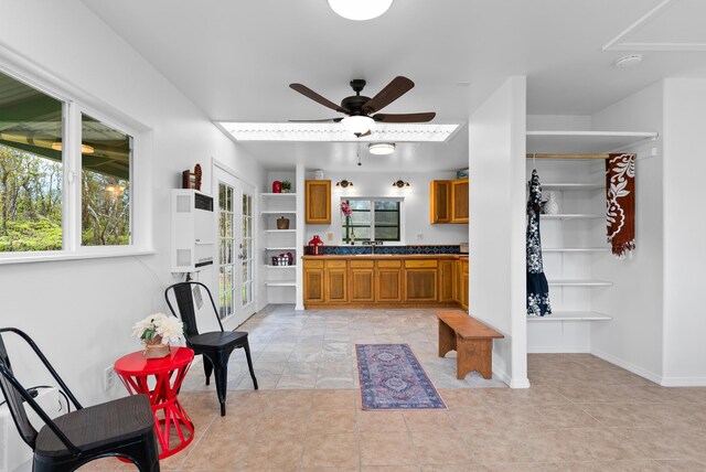 11-2449 Ohialani Rd, Volcano, HI 96785 - kitchen featuring brown cabinetry, ceiling fan, baseboards, dark countertops, and a sink