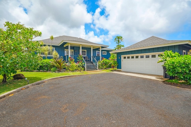 2650 Halalu St, Koloa, HI 96756 - view of front of property with board and batten siding, roof with shingles, a porch, driveway, and a front lawn