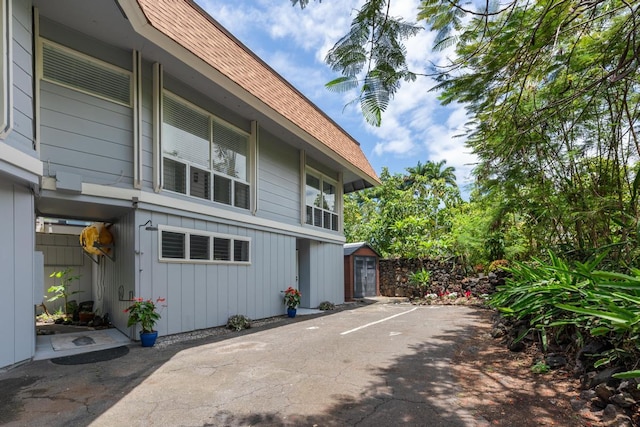 75-6150 Alii Dr Unit 8, Kailua-Kona, HI 96740 - view of property exterior featuring a shingled roof, a patio, and board and batten siding