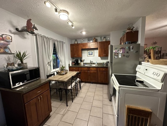 14-682 Kehau Rd, Pahoa, HI 96778 - kitchen featuring stainless steel appliances, dark countertops, light tile patterned floors, a sink, and a textured ceiling