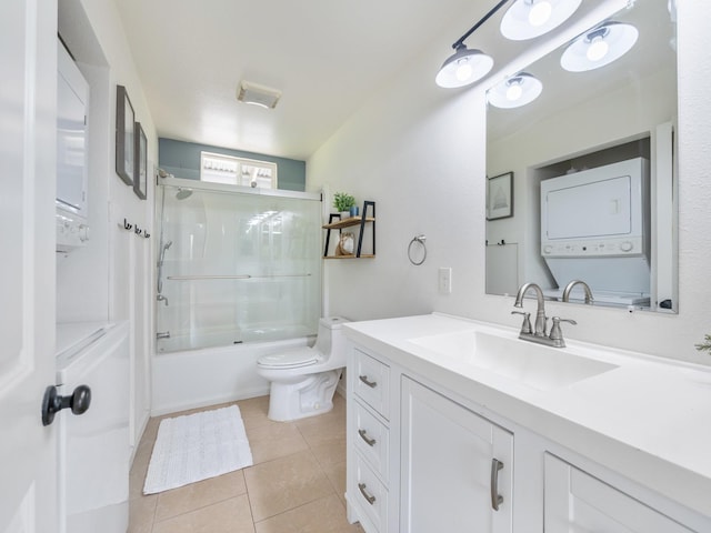 12-7038 Kehauopuna St, Pahoa, HI 96778 - bathroom featuring stacked washing machine and dryer, vanity, toilet, tile patterned floors, and bath / shower combo with glass door