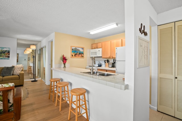 4330 Kauai Beach Dr Unit E5, Lihue, HI 96766 - kitchen featuring white appliances, a kitchen bar, a textured ceiling, light wood finished floors, and light brown cabinetry