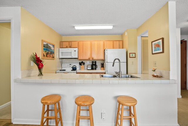4330 Kauai Beach Dr Unit E5, Lihue, HI 96766 - kitchen with white appliances, a peninsula, a breakfast bar, decorative backsplash, and a textured ceiling