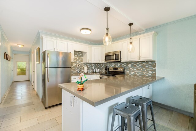 69-1647 Puako Beach Dr Unit 105, Kamuela, HI 96743 - kitchen featuring stainless steel appliances, decorative backsplash, a peninsula, white cabinetry, and crown molding