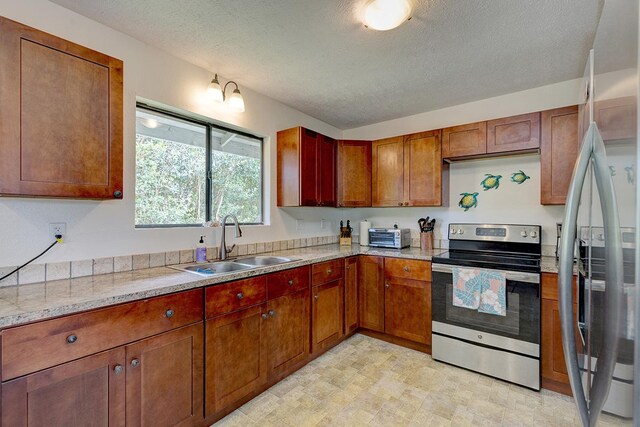 16-2038 Maile Way, Pahoa, HI 96778 - kitchen featuring appliances with stainless steel finishes, a sink, a textured ceiling, and brown cabinetry