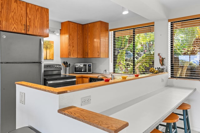 78-6737 Walua Rd, Kailua-Kona, HI 96740 - kitchen with appliances with stainless steel finishes, light countertops, brown cabinetry, a kitchen breakfast bar, and a sink