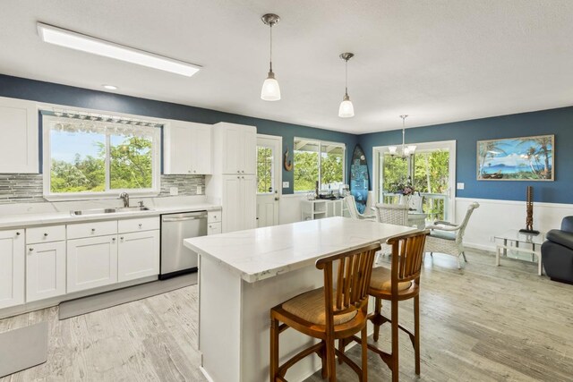 15-1653 28th Ave, Keaau, HI 96749 - kitchen featuring stainless steel dishwasher, a sink, white cabinetry, light wood-style flooring, and wainscoting