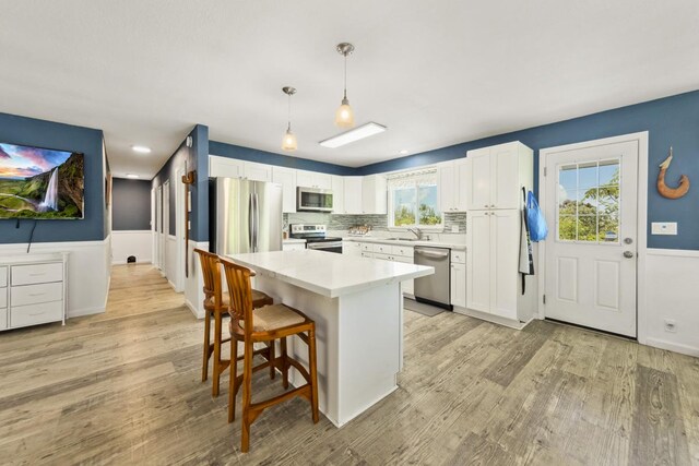 15-1653 28th Ave, Keaau, HI 96749 - kitchen with appliances with stainless steel finishes, white cabinetry, light countertops, a breakfast bar, and light wood-style floors