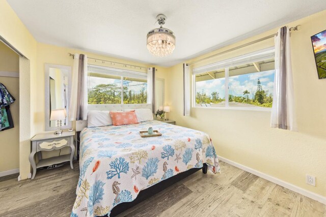 15-1653 28th Ave, Keaau, HI 96749 - bedroom featuring baseboards, wood finished floors, and a chandelier