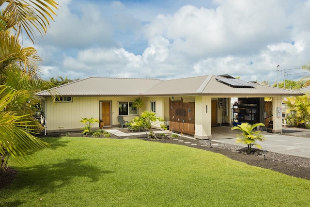 16-2081 Ohia Dr, Pahoa, HI 96778 - view of front of house featuring concrete driveway, roof mounted solar panels, a front yard, a garage, and a metal roof