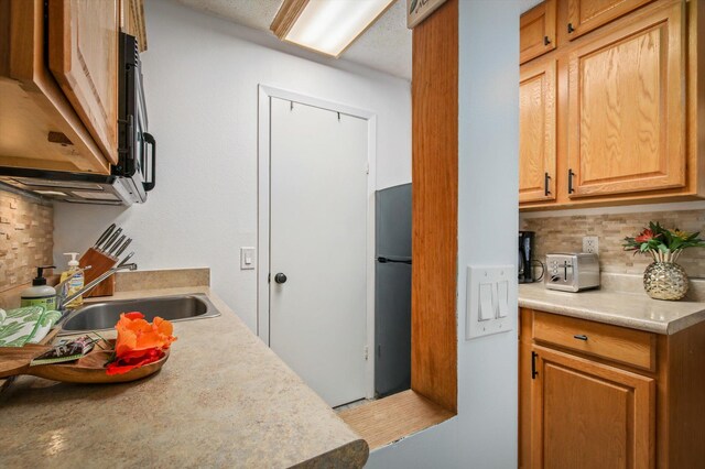 75-5776 Kuakini Hwy Unit 123, Kailua-Kona, HI 96740 - kitchen featuring backsplash, a sink, light countertops, and freestanding refrigerator
