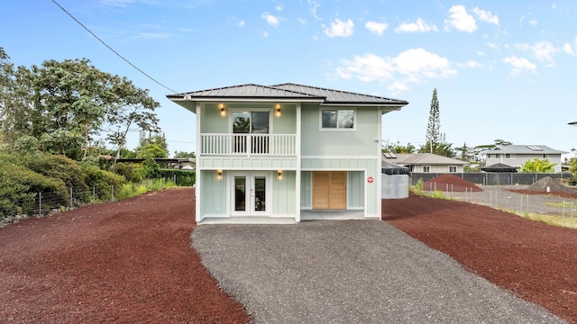 16-2143 Uilani Dr, Pahoa, HI 96778 - view of front of house with french doors, metal roof, gravel driveway, board and batten siding, and a balcony