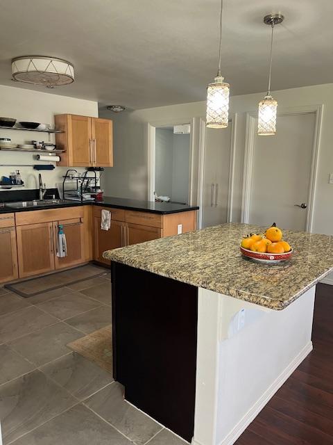 470 Hoopuni St, Hilo, HI 96720 - kitchen featuring open shelves, dark stone countertops, a peninsula, pendant lighting, and brown cabinets