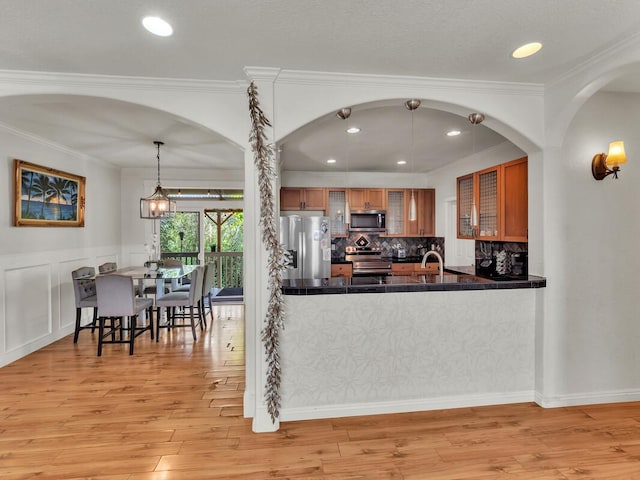 16-2069 Leilani Dr, Pahoa, HI 96778 - kitchen with stainless steel appliances, brown cabinetry, dark countertops, light wood-style floors, and tasteful backsplash