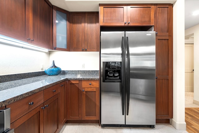 69-1033 Nawahine Pl Unit 1G, Waikoloa, HI 96738 - kitchen with stainless steel fridge, glass insert cabinets, dark stone counters, and brown cabinets