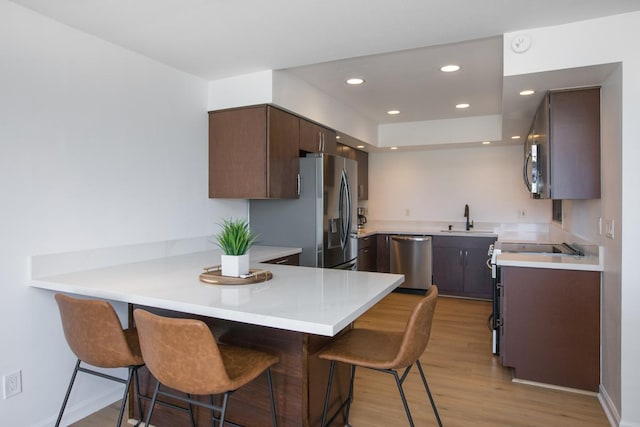 78-7070 Alii Dr Unit B202, Kailua-Kona, HI 96740 - kitchen with stainless steel appliances, a sink, a peninsula, light wood-style floors, and a breakfast bar