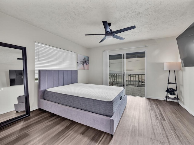 74-5071 Kealapua St, Kailua-Kona, HI 96740 - bedroom featuring wood finished floors, access to exterior, multiple windows, baseboards, and a textured ceiling