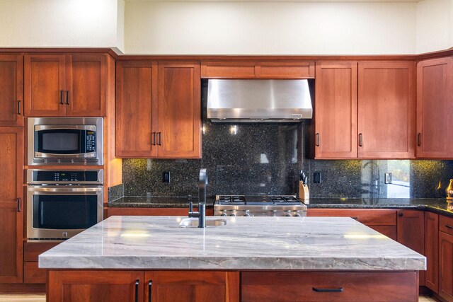 73-1138 Hamo St, Kailua-Kona, HI 96740 - kitchen with stainless steel appliances, exhaust hood, a sink, a center island with sink, and stone countertops