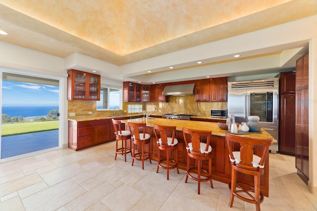 73-4558 Kukuki St, Kailua-Kona, HI 96740 - kitchen featuring wall chimney exhaust hood, a raised ceiling, light countertops, tasteful backsplash, and stainless steel appliances